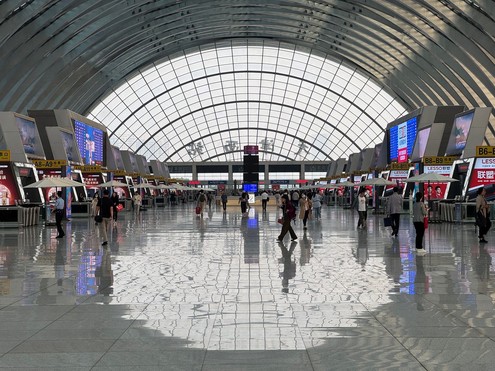 A bustling modern airport terminal with geometric ceiling design and reflective floors.