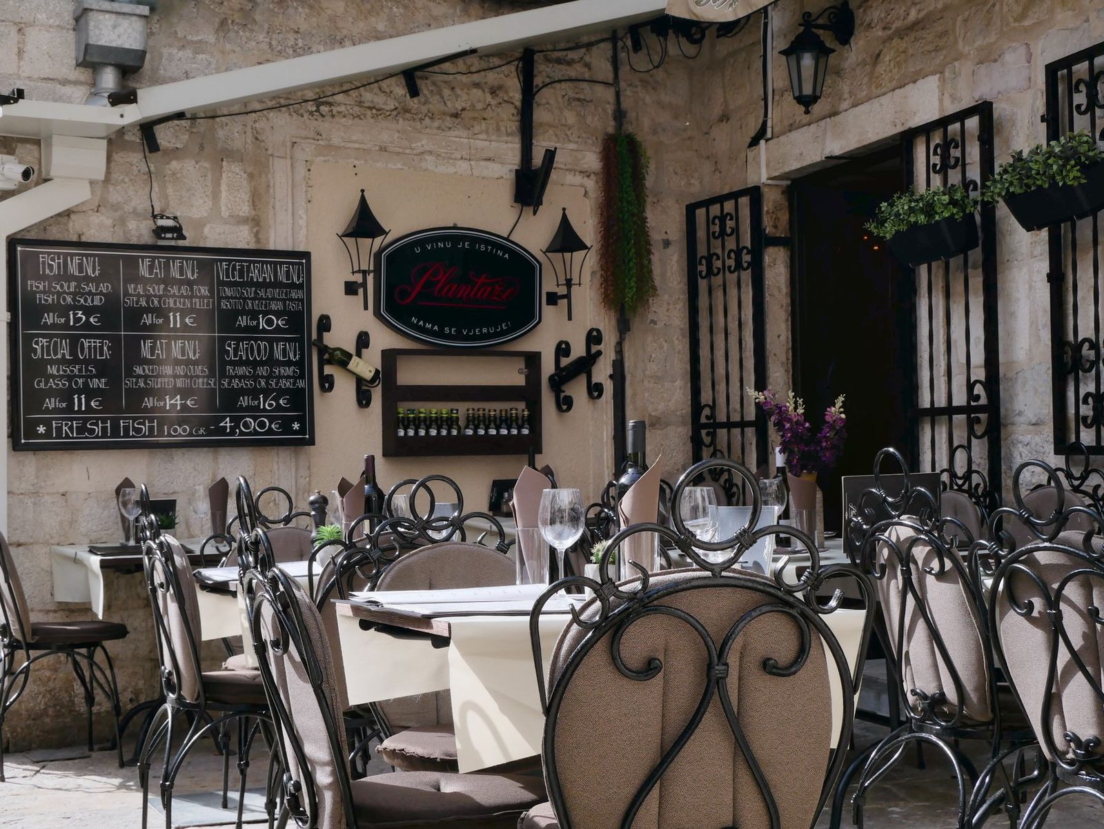 Cozy outdoor dining area of a picturesque bistro, set in a sunlit, rustic alley. Perfect for a quaint meal.