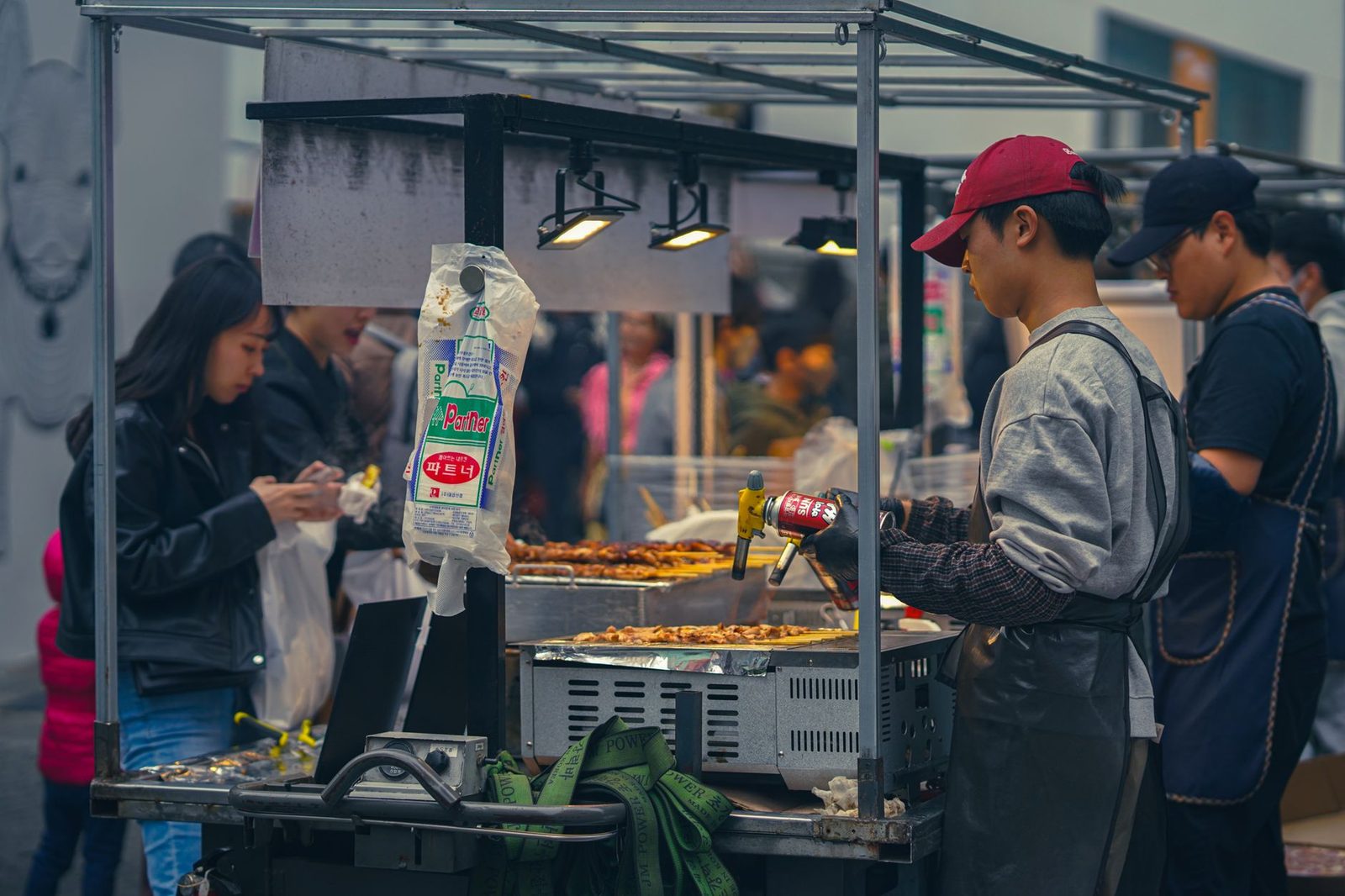 Vibrant street food scene at a bustling Seoul market, featuring vendors and diners.