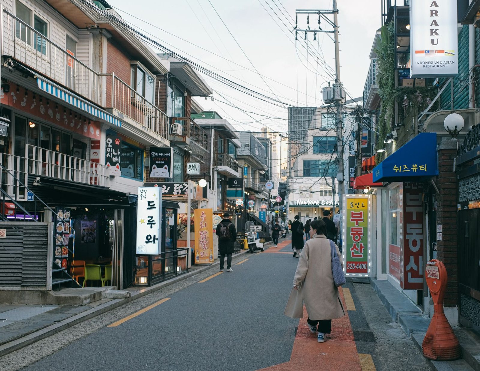 Vibrant urban street with diverse stores and pedestrians in Seoul's downtown district.