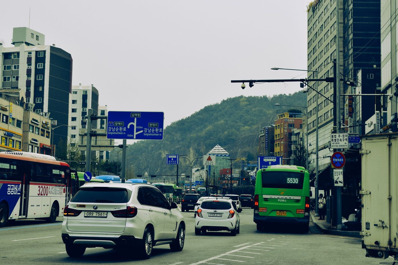 Bustling urban street in Seoul with diverse traffic and cityscape views.