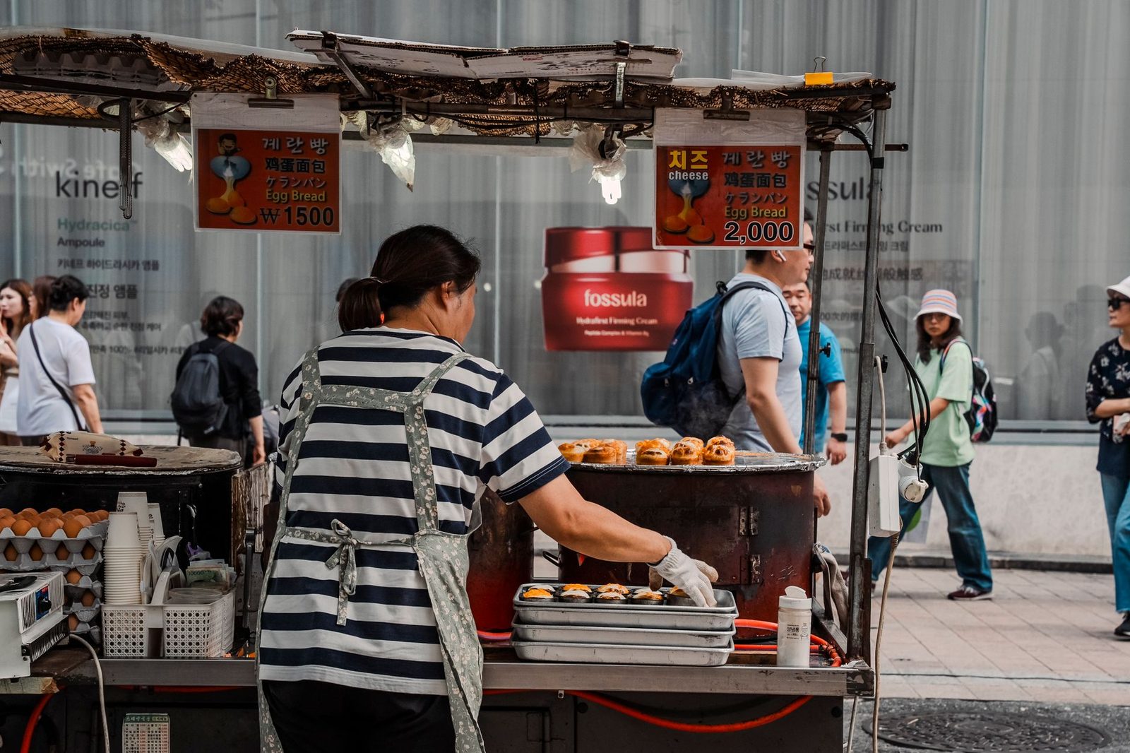 Woman preparing Korean egg bread at an outdoor market stall in Seoul, South Korea.
