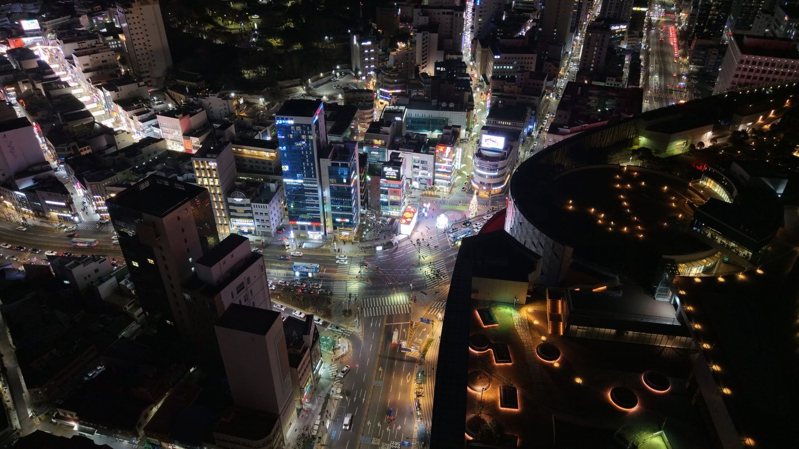 Stunning aerial view of Busan at night, showcasing the city's vibrant nightlife and illuminated architecture.