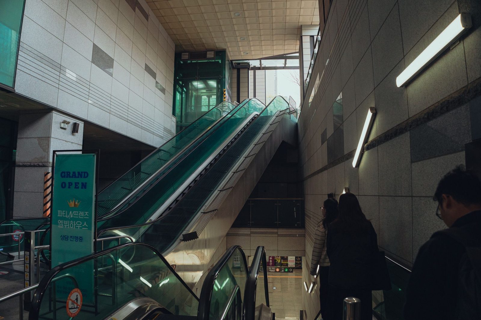Passengers using escalator in Seoul subway, showcasing modern architecture and urban lifestyle.