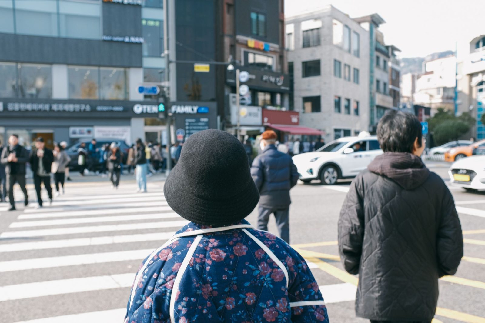 Street scene in Seoul capturing pedestrians at a crosswalk on a bustling day.
