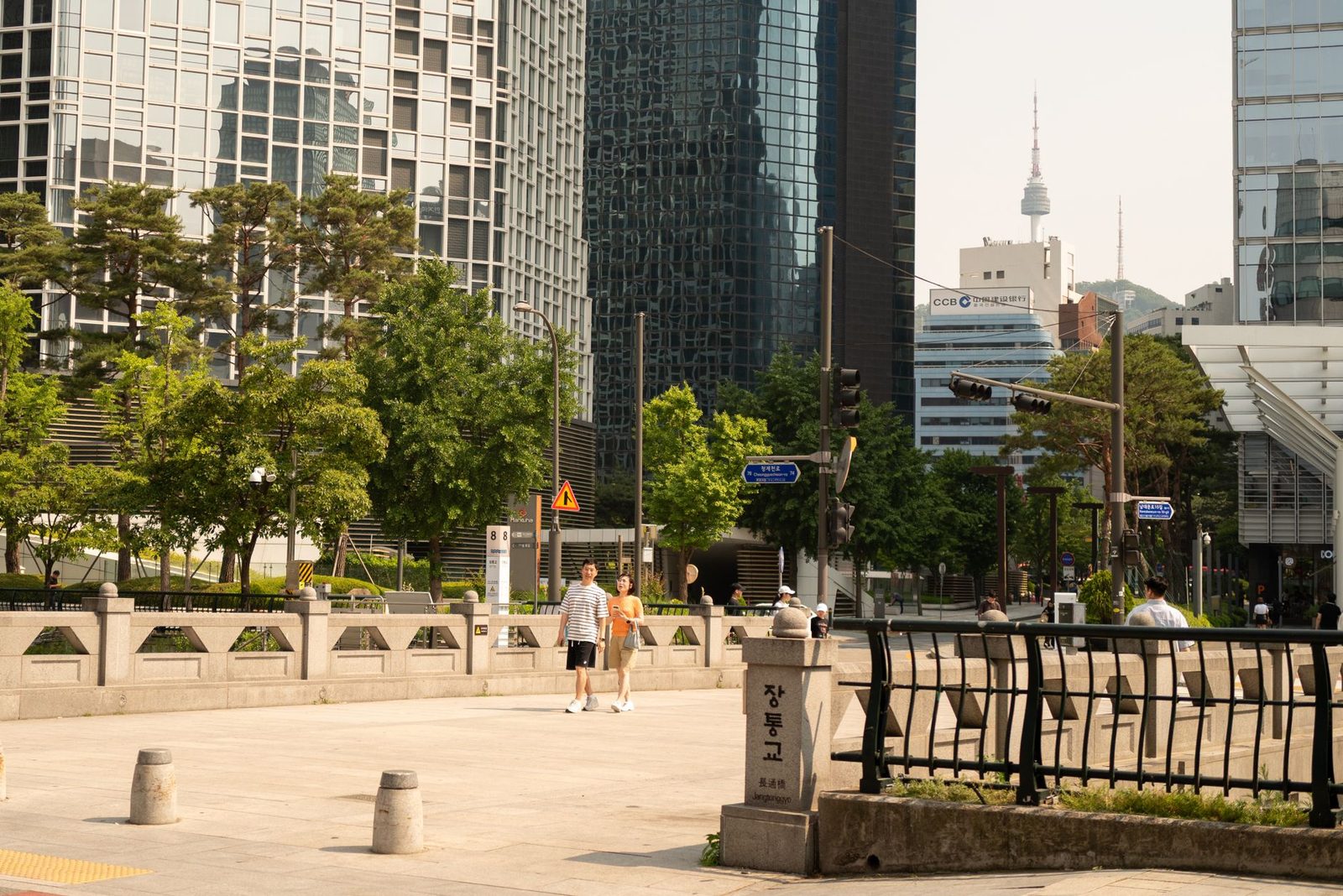 Street view of Seoul with modern skyscrapers and Namsan Tower in background. Summer setting.