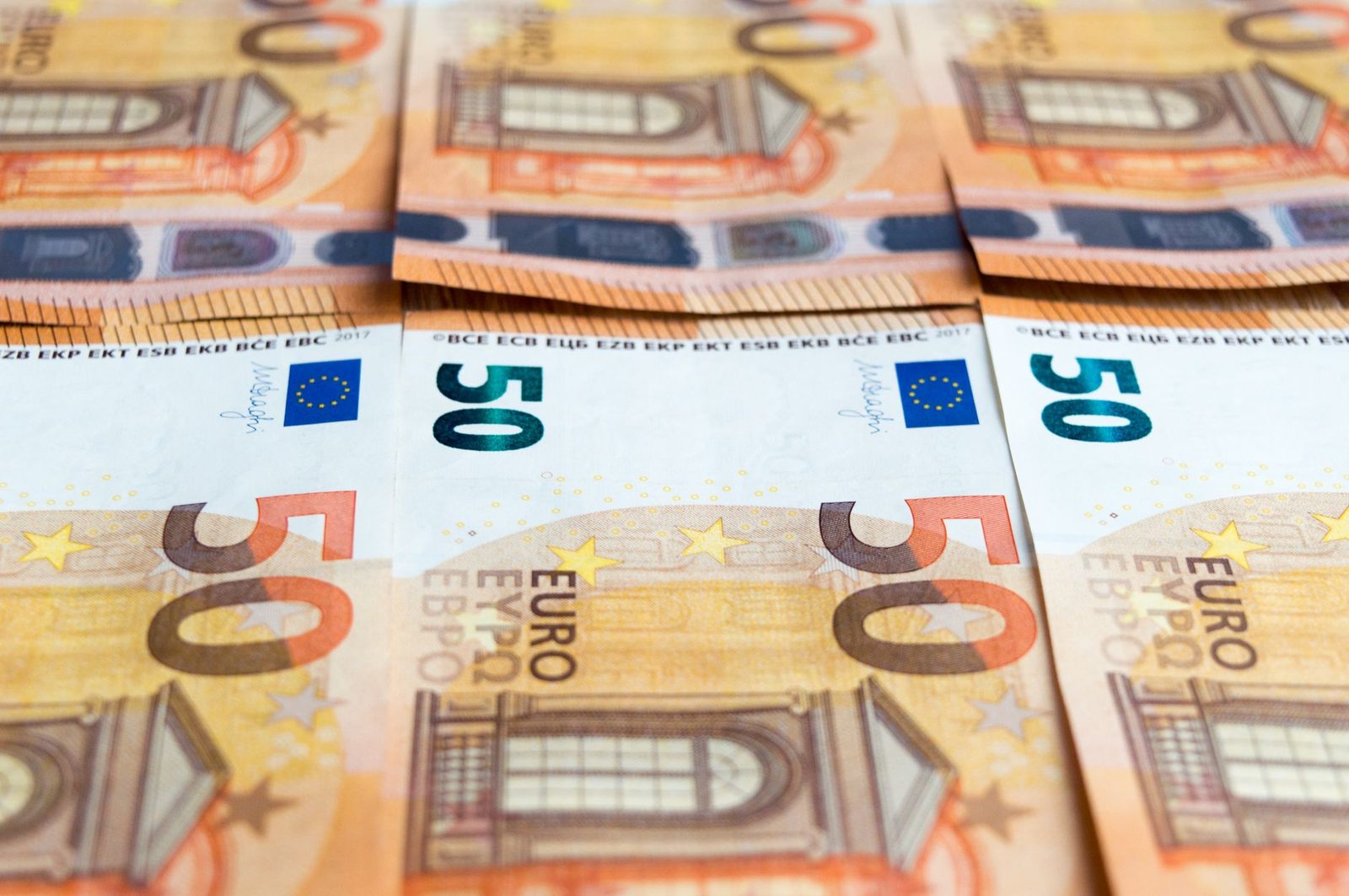 Detailed image of multiple 50 Euro bills stacked, showcasing currency design.