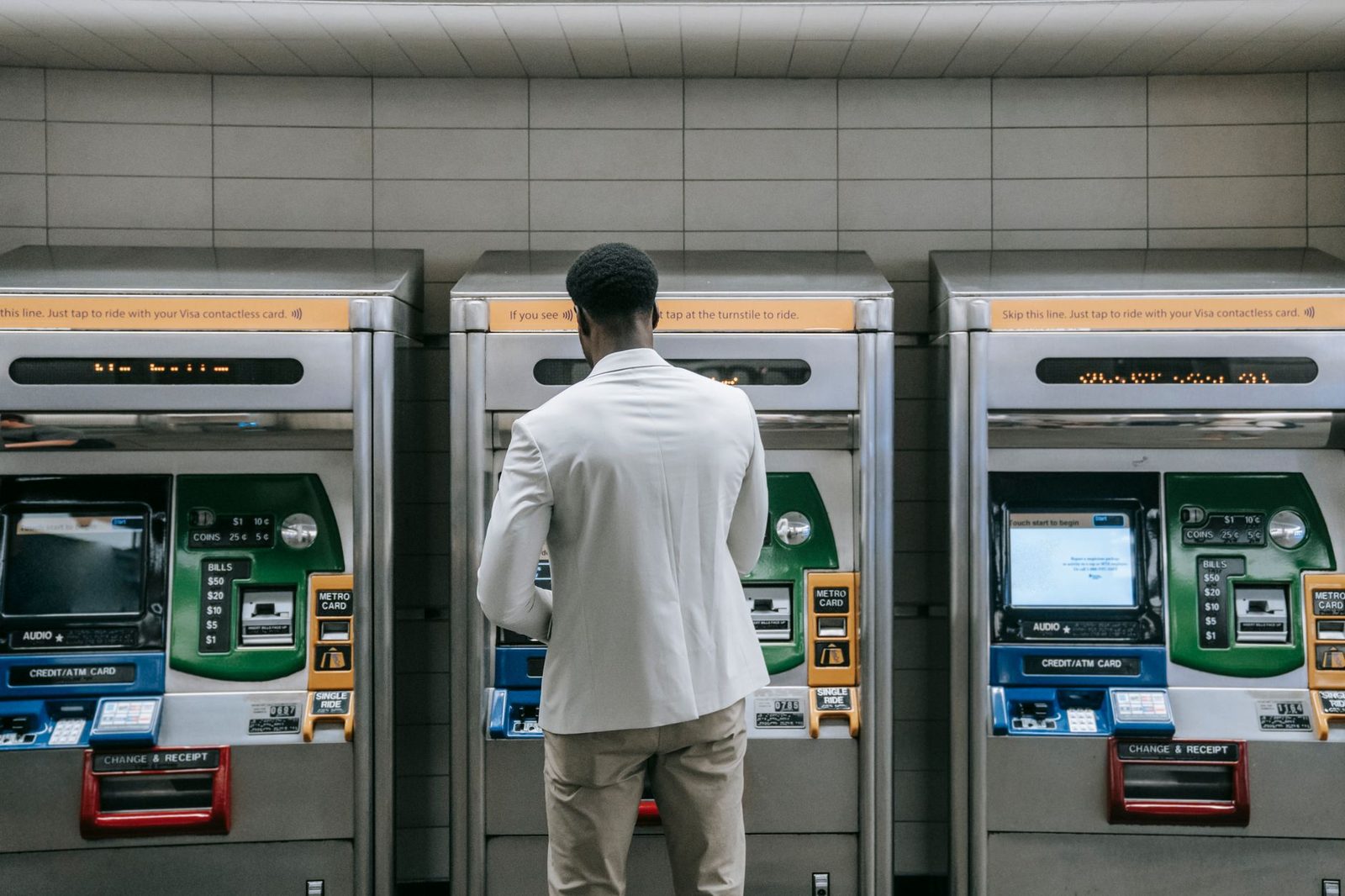 Business professional using a metro ticket machine at a transit station.
