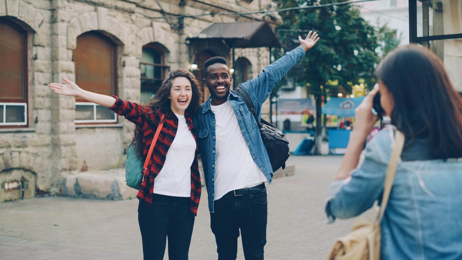 Two cheerful travelers posing for a photo in a city street, capturing joyful memories.