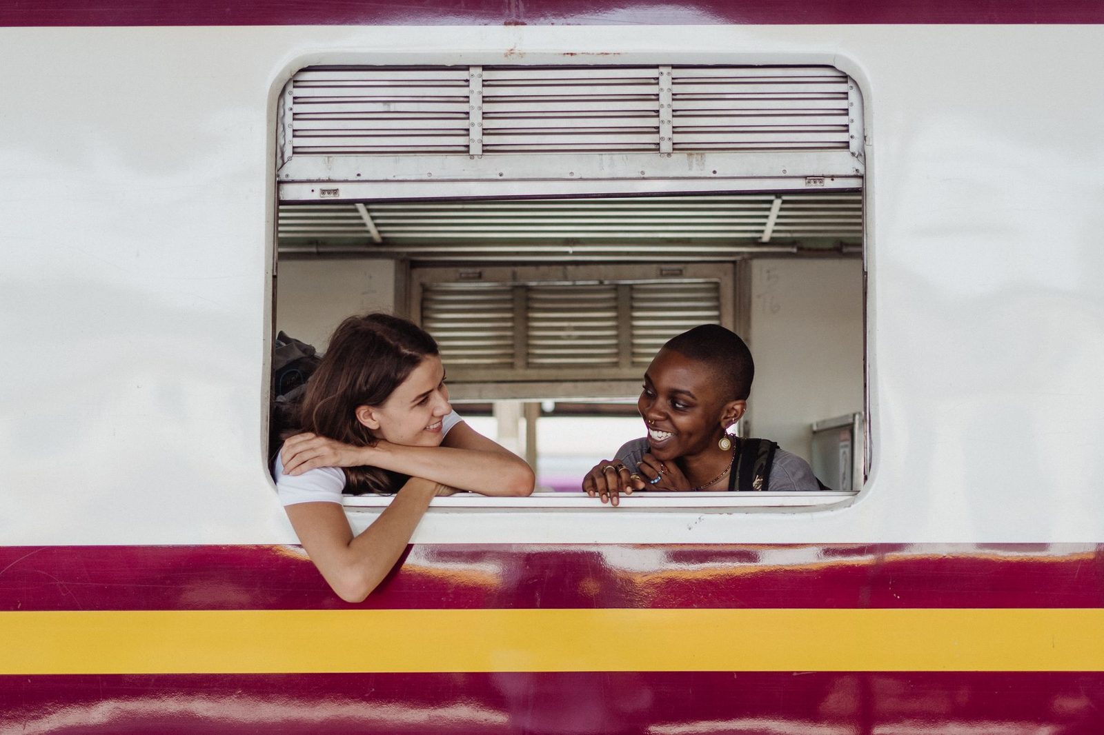 Two smiling women enjoying a train ride, capturing a moment of friendship and travel.