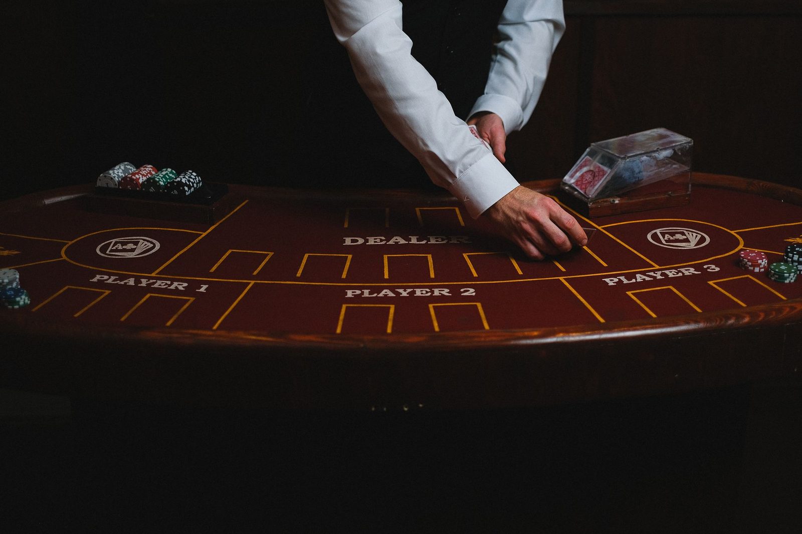 A croupier deals cards on a dimly lit casino table, showcasing gambling atmosphere.