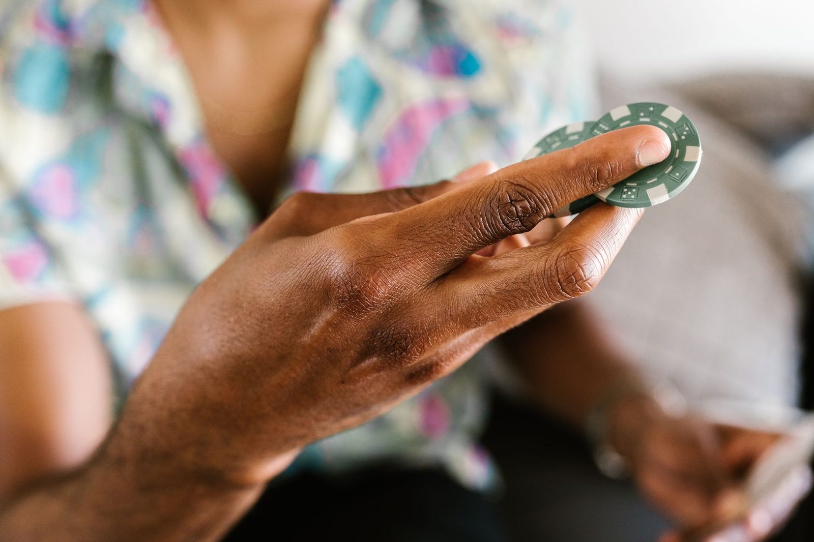 A detailed view of a hand holding a poker chip with a blurred background, emphasizing gambling and fun.