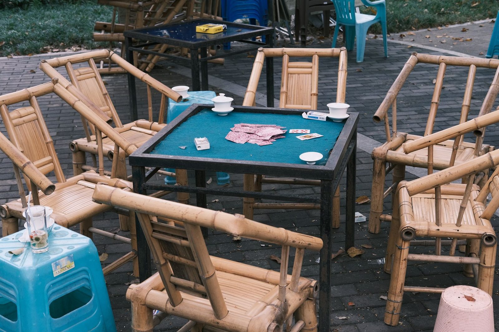 Bamboo chairs surrounding a poker table outdoors, suggesting a casual gathering or game setting.
