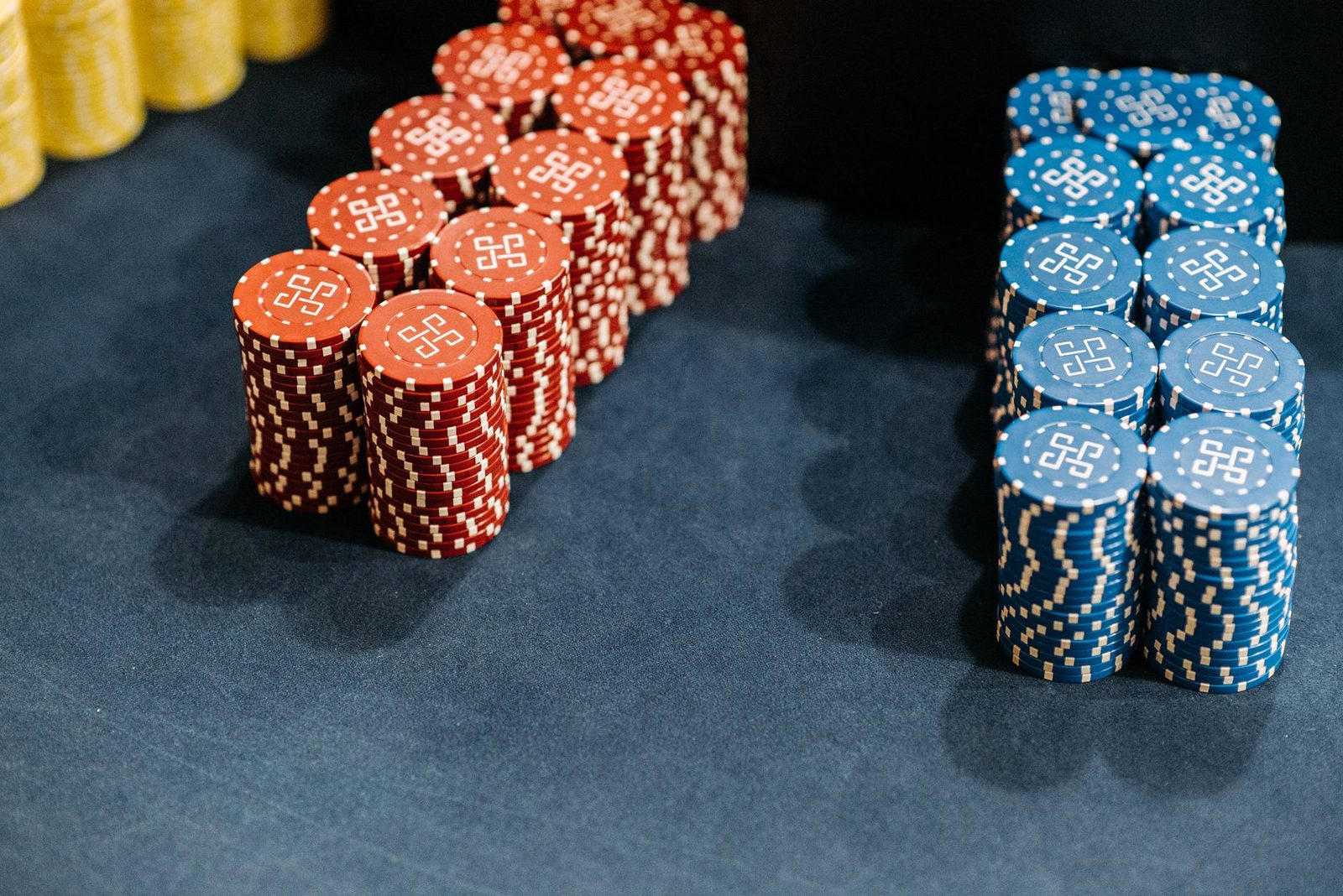 Close-up of neatly stacked red and blue casino chips on a gaming table.