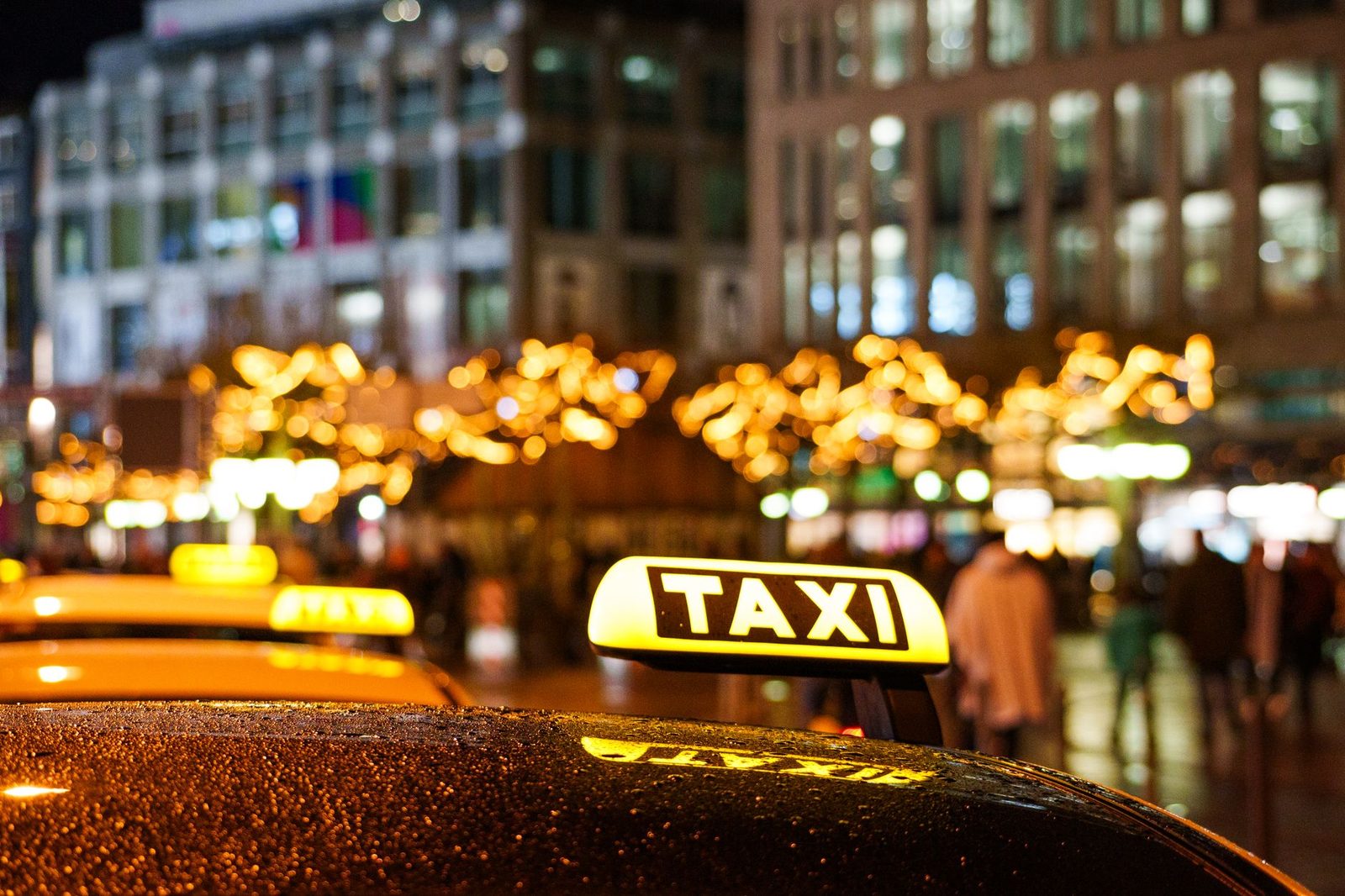 Glistening taxis at night with festive city lights, creating a vibrant urban atmosphere.