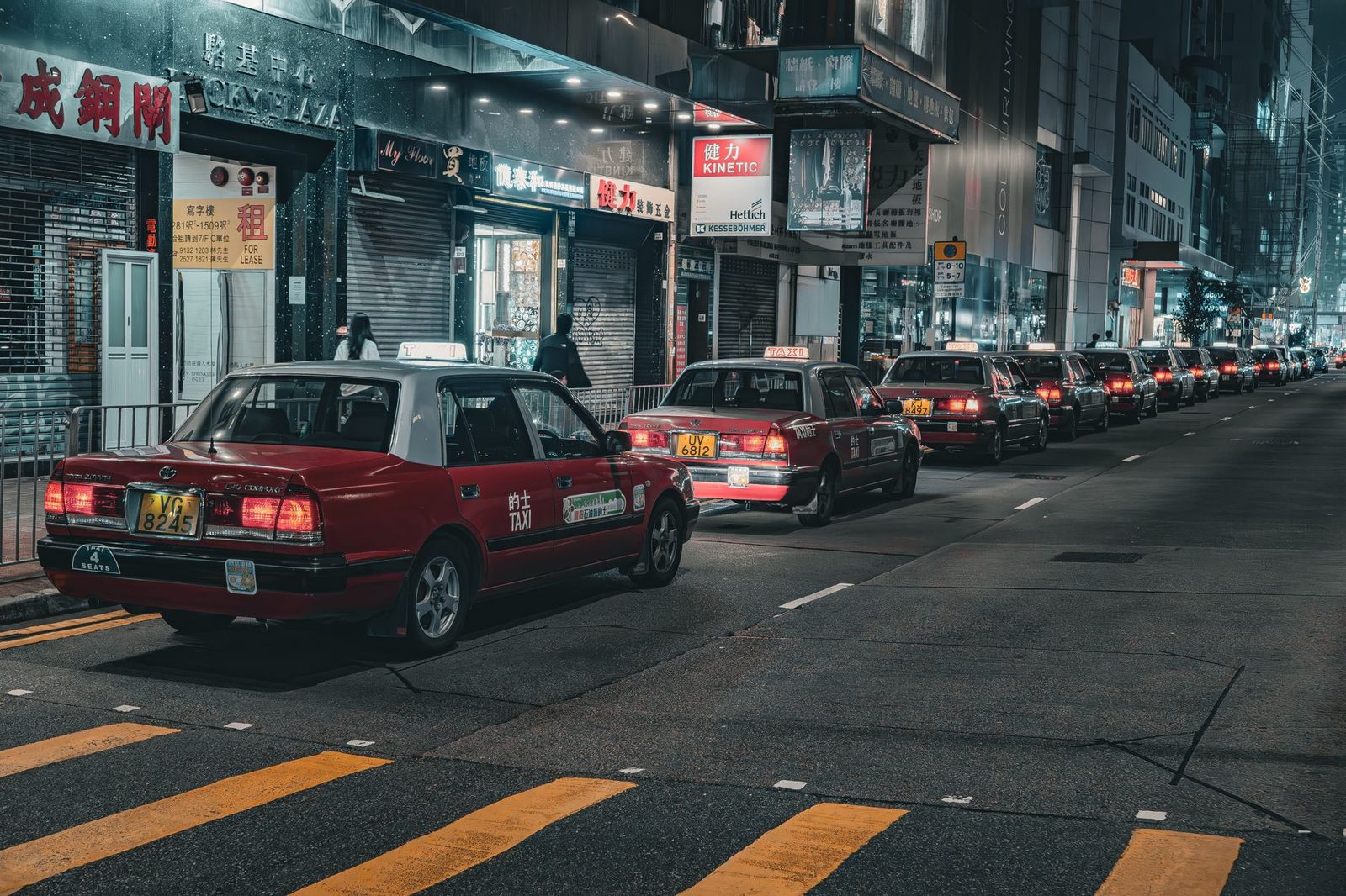A street in Hong Kong bustling with red taxis at night, capturing urban life and city lights.