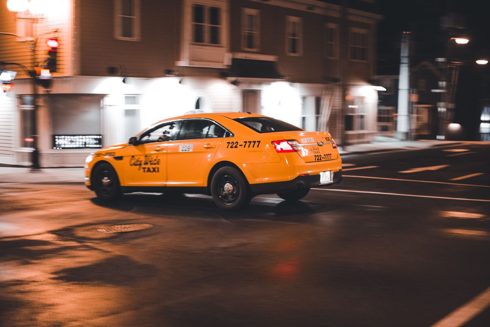 Dynamic yellow taxi captured in motion on a city street at night.