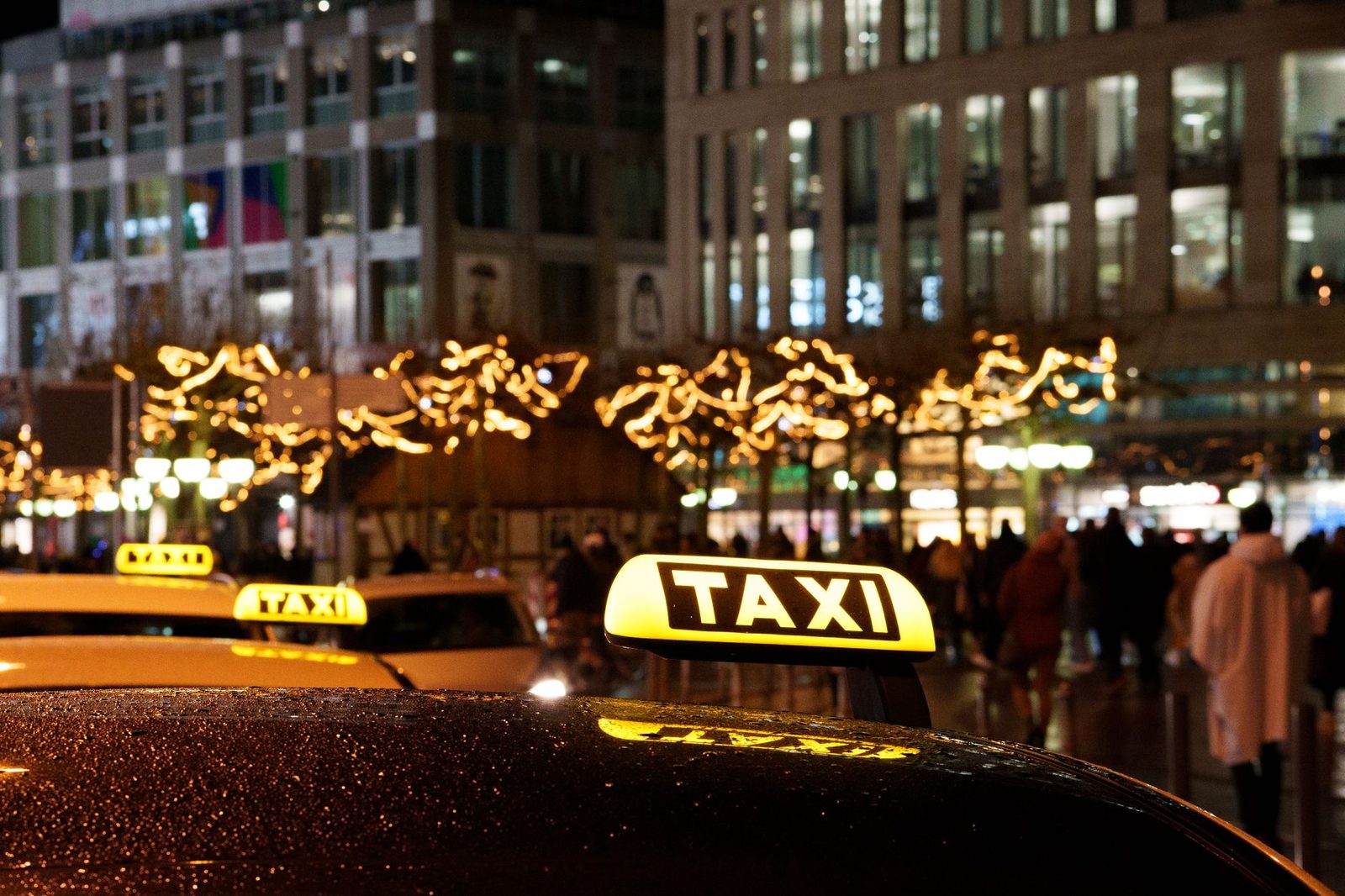 A vibrant city scene at night featuring taxis with illuminated signs and festive decorations.