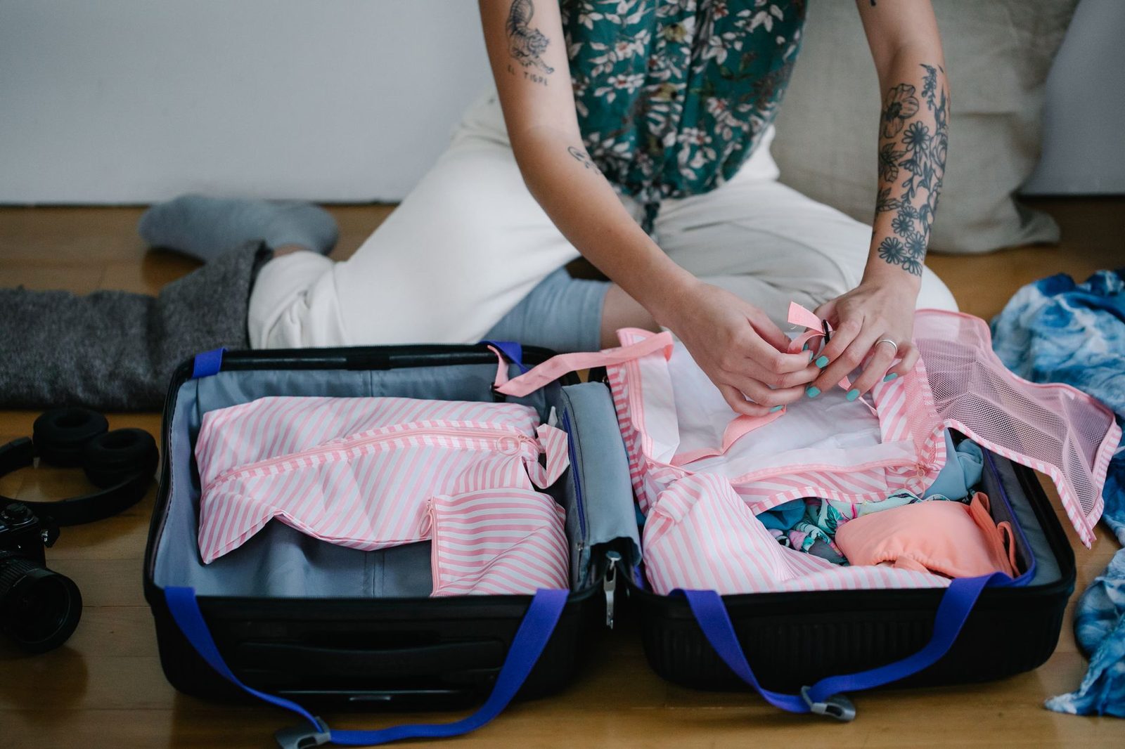 A woman packing her travel suitcase on the floor indoors, preparing for a trip.