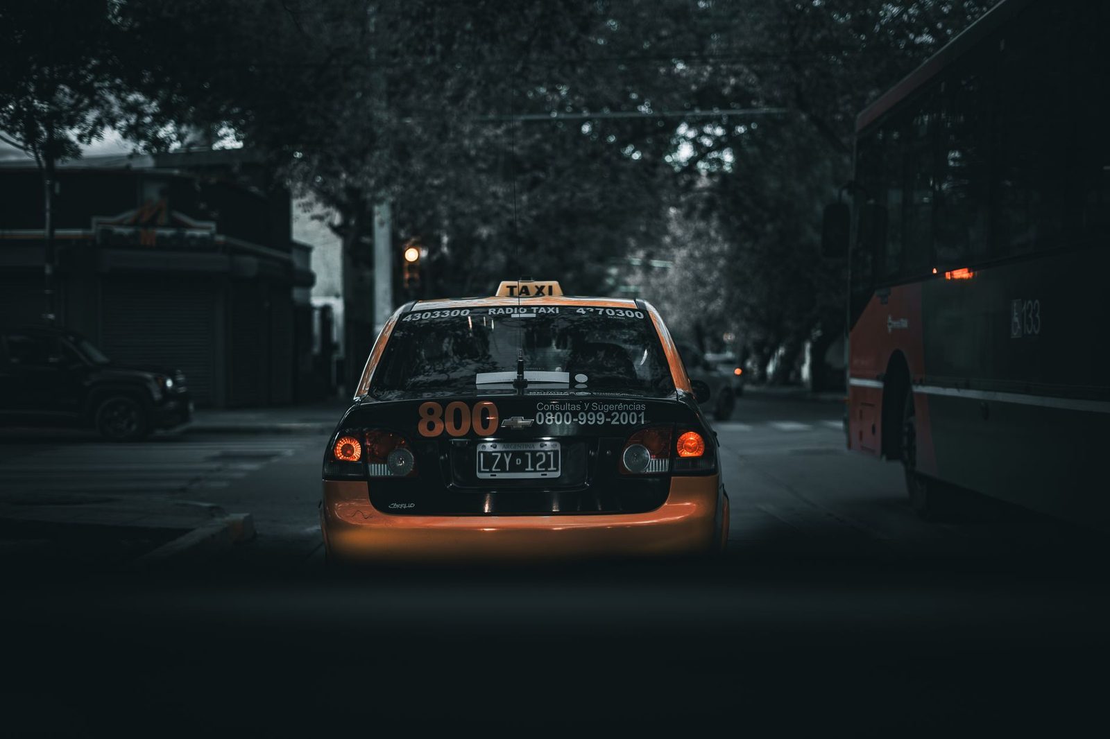 Moody city street with a taxi and bus at night, showcasing urban transportation.