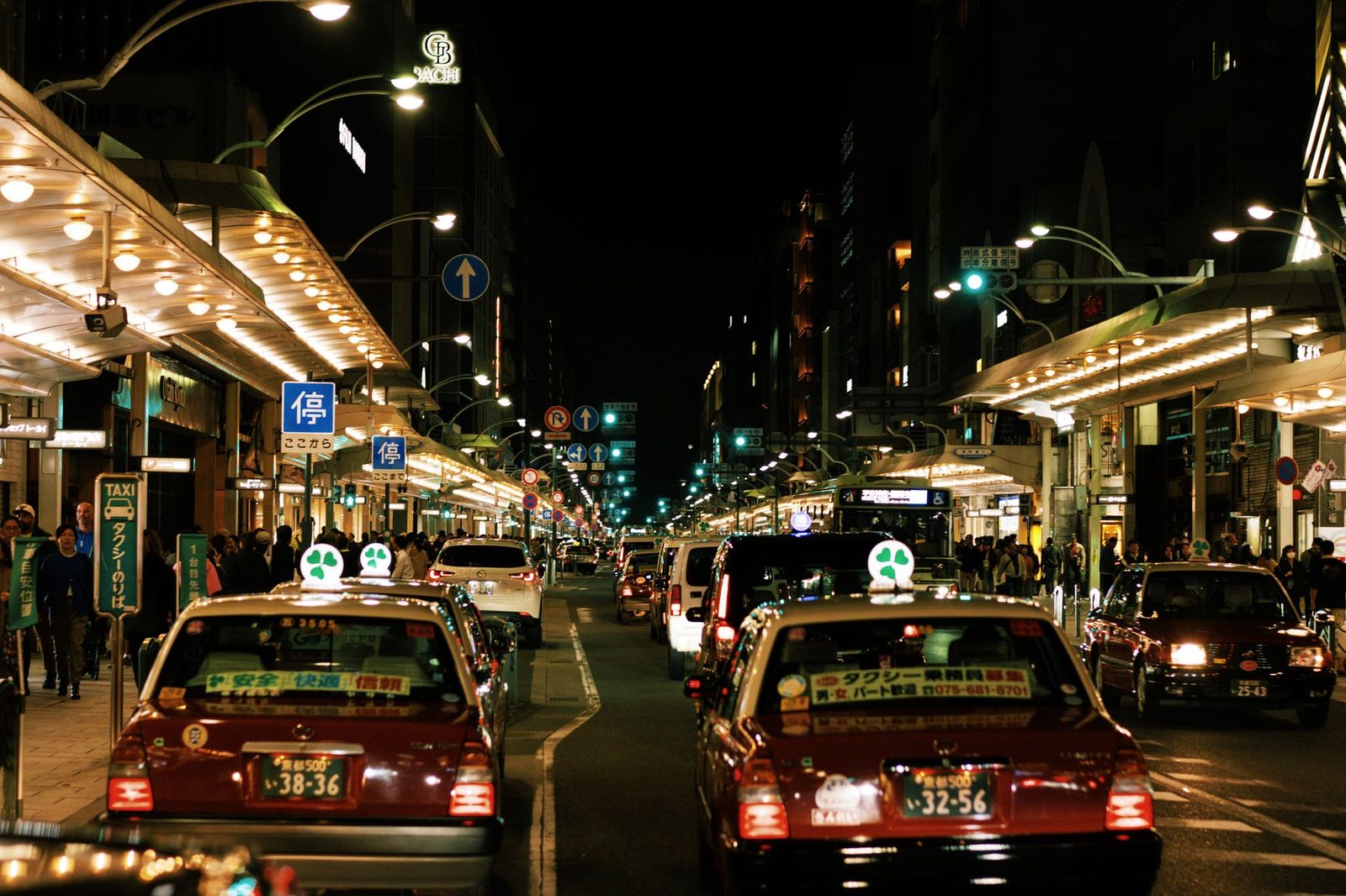Vibrant night scene in Kyoto featuring busy streets and iconic Japanese taxis.