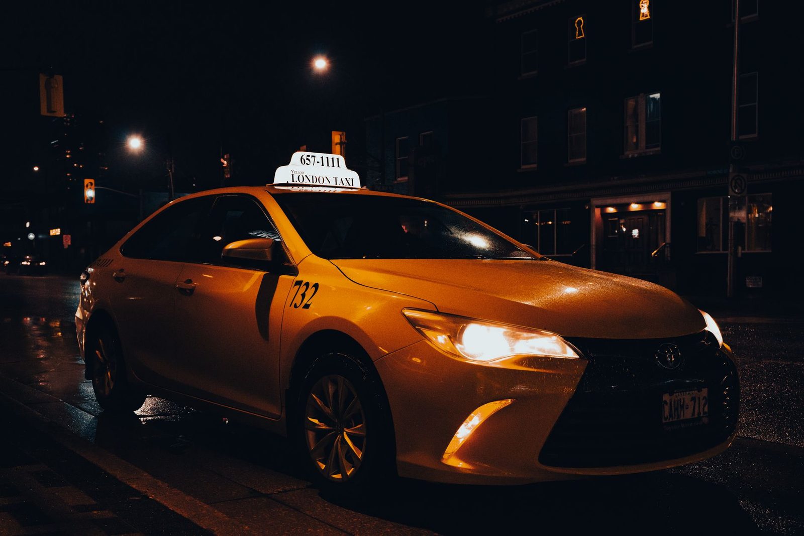 A yellow taxi waiting at night in London, Ontario, Canada. Urban transportation captured with street lights.