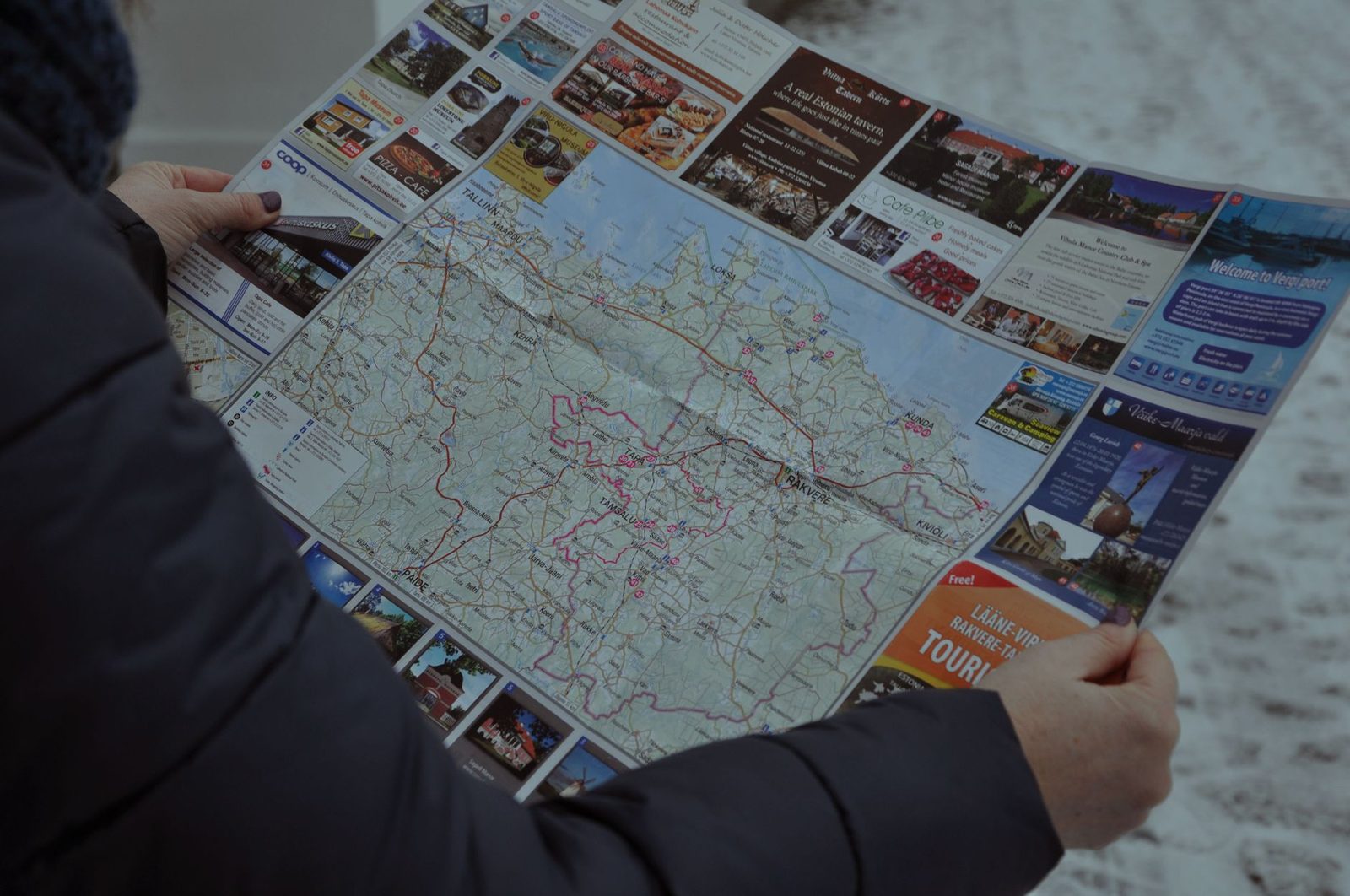 A person examining a detailed map outside during winter, focusing on directions.