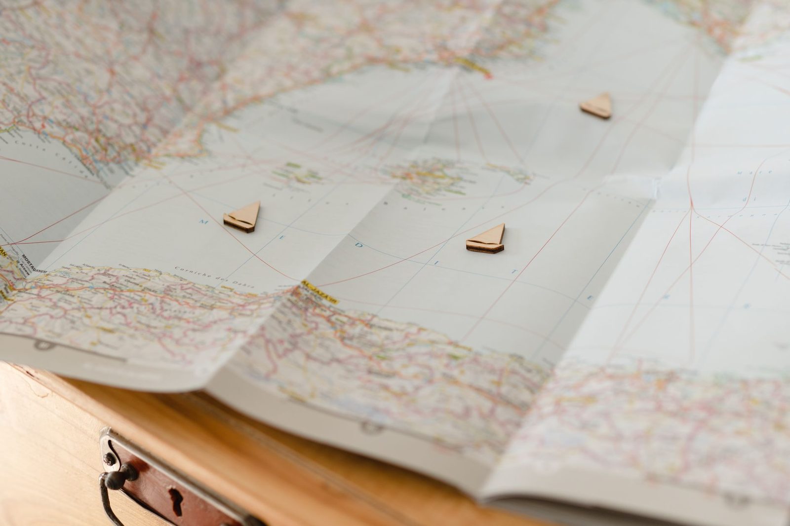World map with wooden ship markers symbolizing travel and exploration laid on a table.