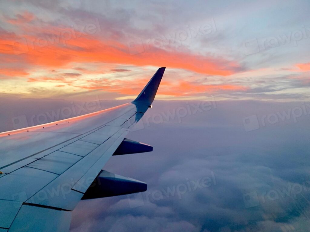 機内の窓から見た飛行機の翼と夕焼けの空